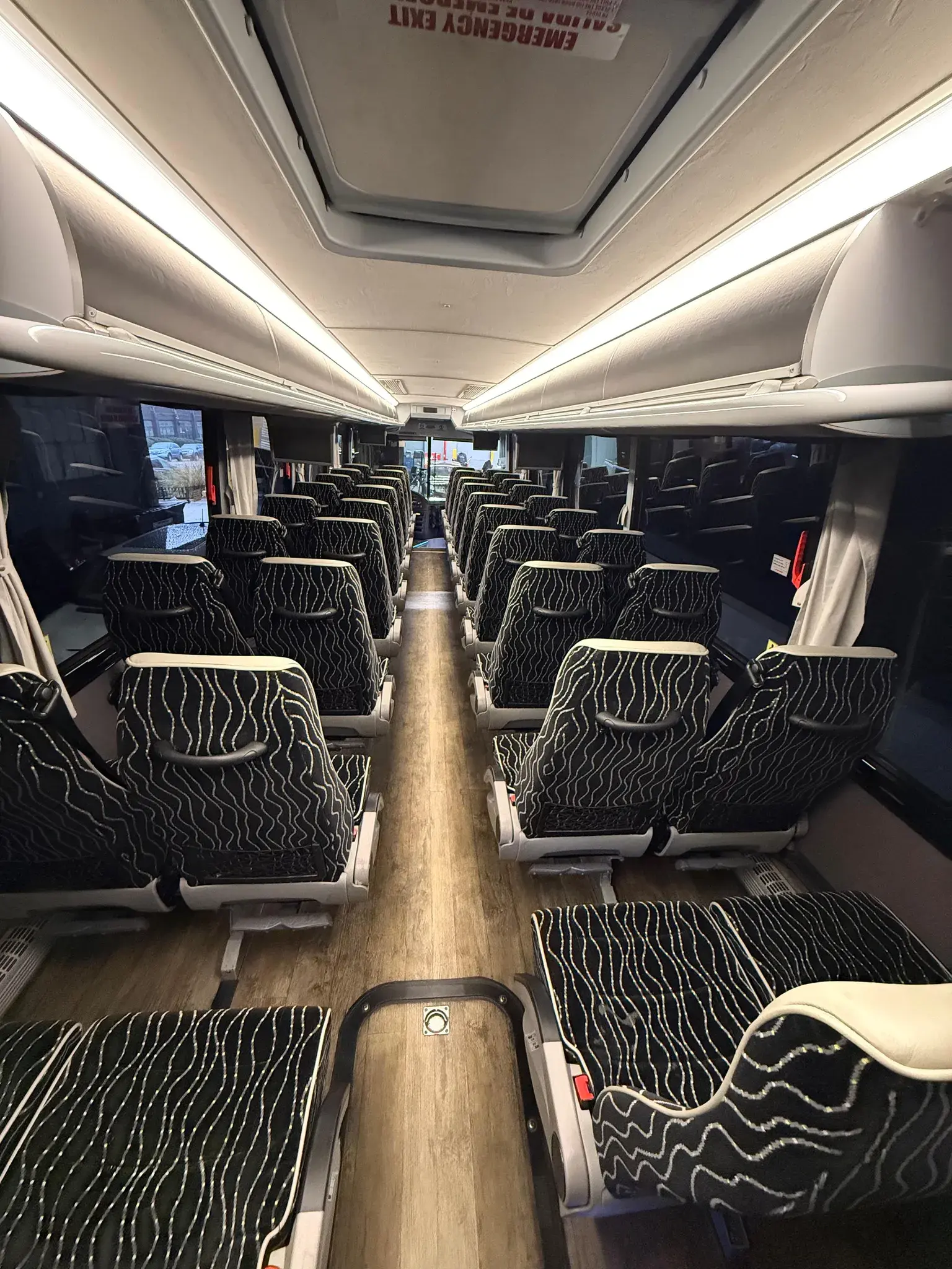 Inside a Golden Class Limo charter bus — rows of black coach seats under warm cabin lighting