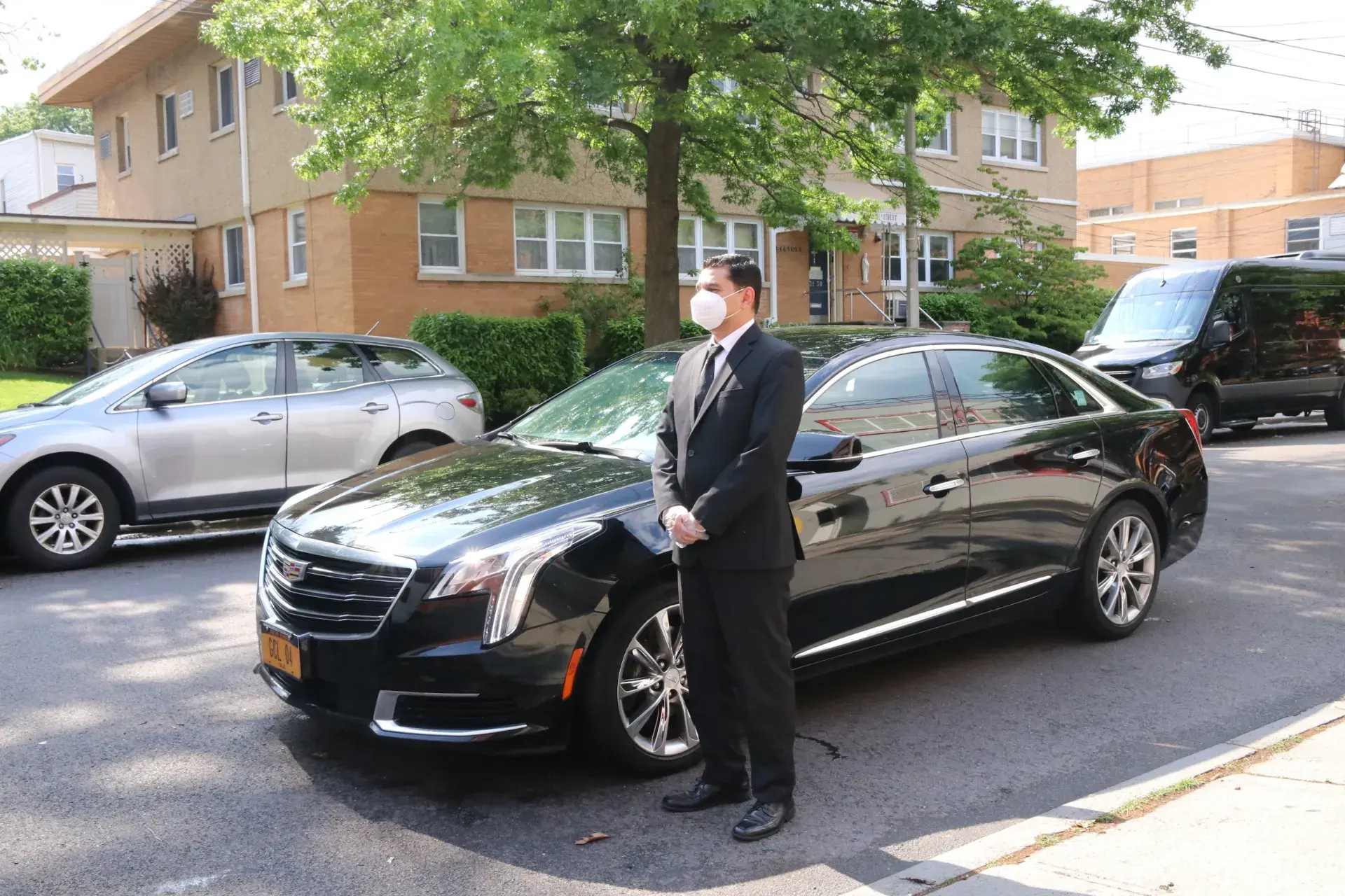 Golden Class Limo chauffeur beside a black Cadillac executive sedan, New York plate GCL 04