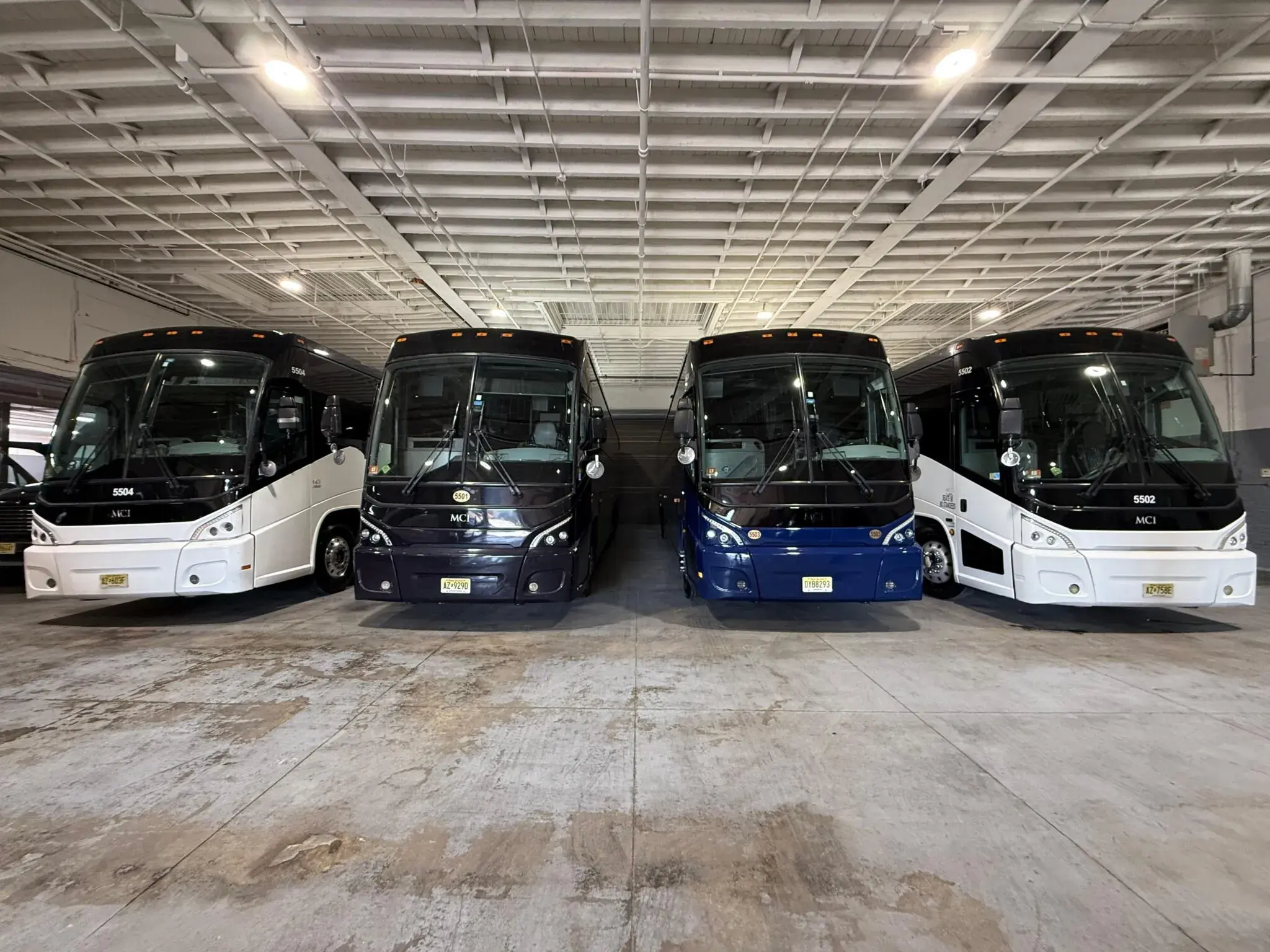Four MCI motor coaches parked head-on inside the operator’s depot
