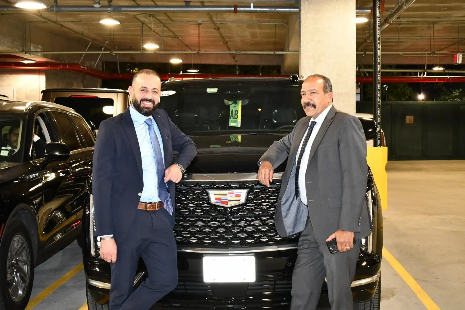 Golden Class Limo team beside a black Cadillac Escalade in the company garage
